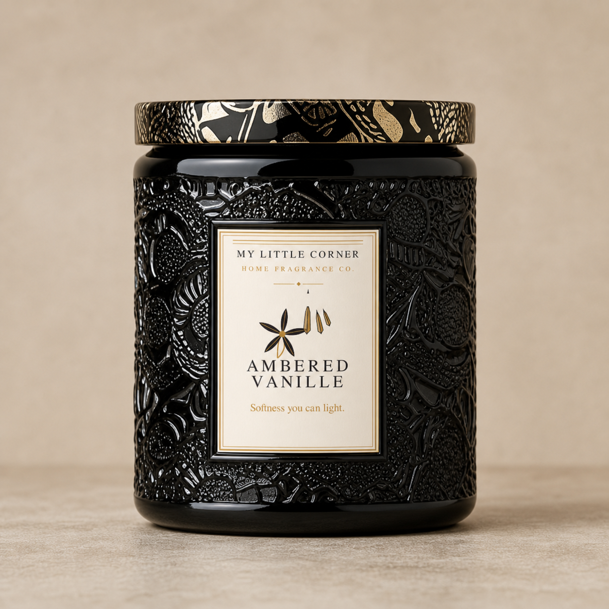 A black scented candle jar with an embossed floral pattern and a cream label reading 'MY LITTLE CORNER HOME FRAGRANCE CO. AMBERED VANILLE'.